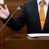 津山市議会の演壇で手を振りながら演説する議員の写真