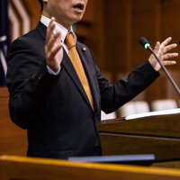 議会中、議論が白熱し激しくジェスチャーをする議員の写真