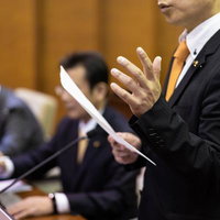 紙の資料を手に議論を深める議員たちの討論の写真