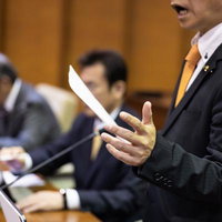 津山市議会の議場で手振りを交えて発言する議員のスピーチシーンの写真