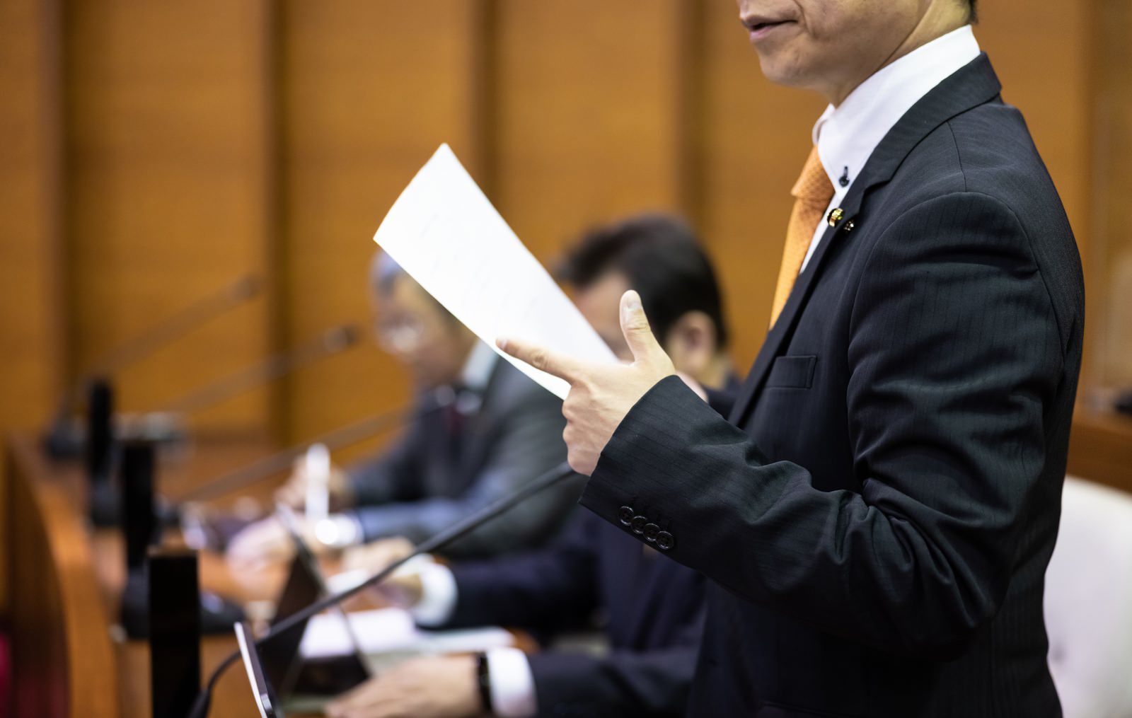 市議会で資料を持って発言する政治家