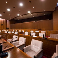 津山市議会の議場、前三列の議員席と後ろの報道関係者席、傍聴席の写真