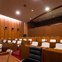 天井が高い津山市議会の本会議場の議員席と議場内観の写真