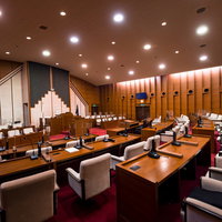 誰もいなくても厳かな津山市議会の議場内の議員席と議長席の写真