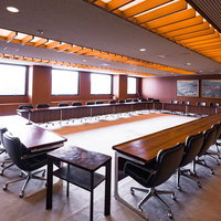 誰もいない全員協議会室で整列する議席と演壇（津山市議会）の写真