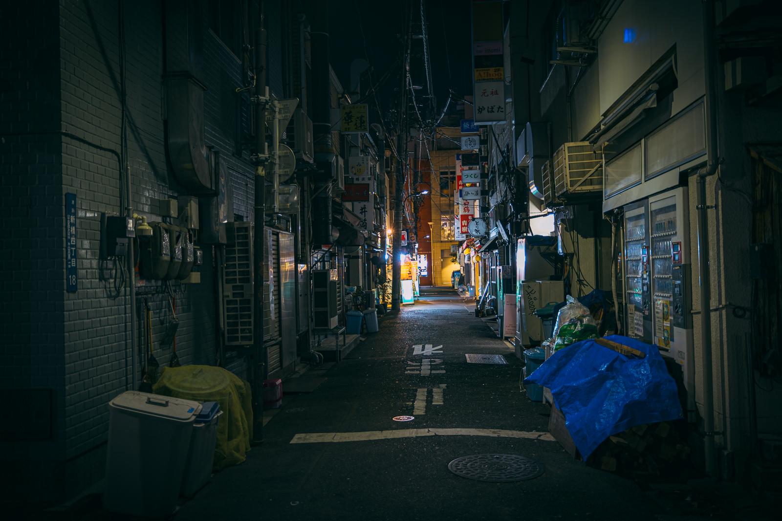 深夜の新橋の路地裏で、両側にスナックと飲み屋が立ち並ぶ夜景