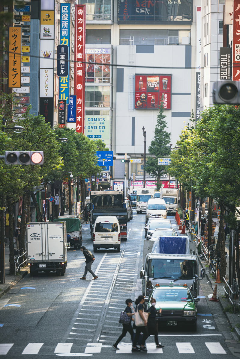 新宿区役所通りで信号待ちをする複数の車両と横断歩道を渡る人々