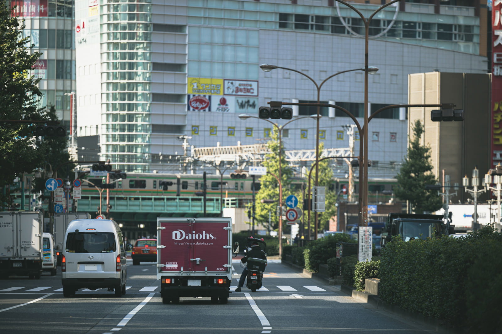 信号で停車している車両とバイクが写る交差点の風景