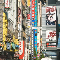 新宿の路地から見上げたカラフルな袖看板とゴジラの頭の写真