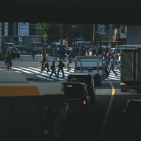 夜の新宿で信号待ちする車両と横断歩道を渡る歩行者の写真