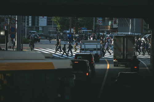 夜の新宿で信号待ちする車両と横断歩道を渡る歩行者
