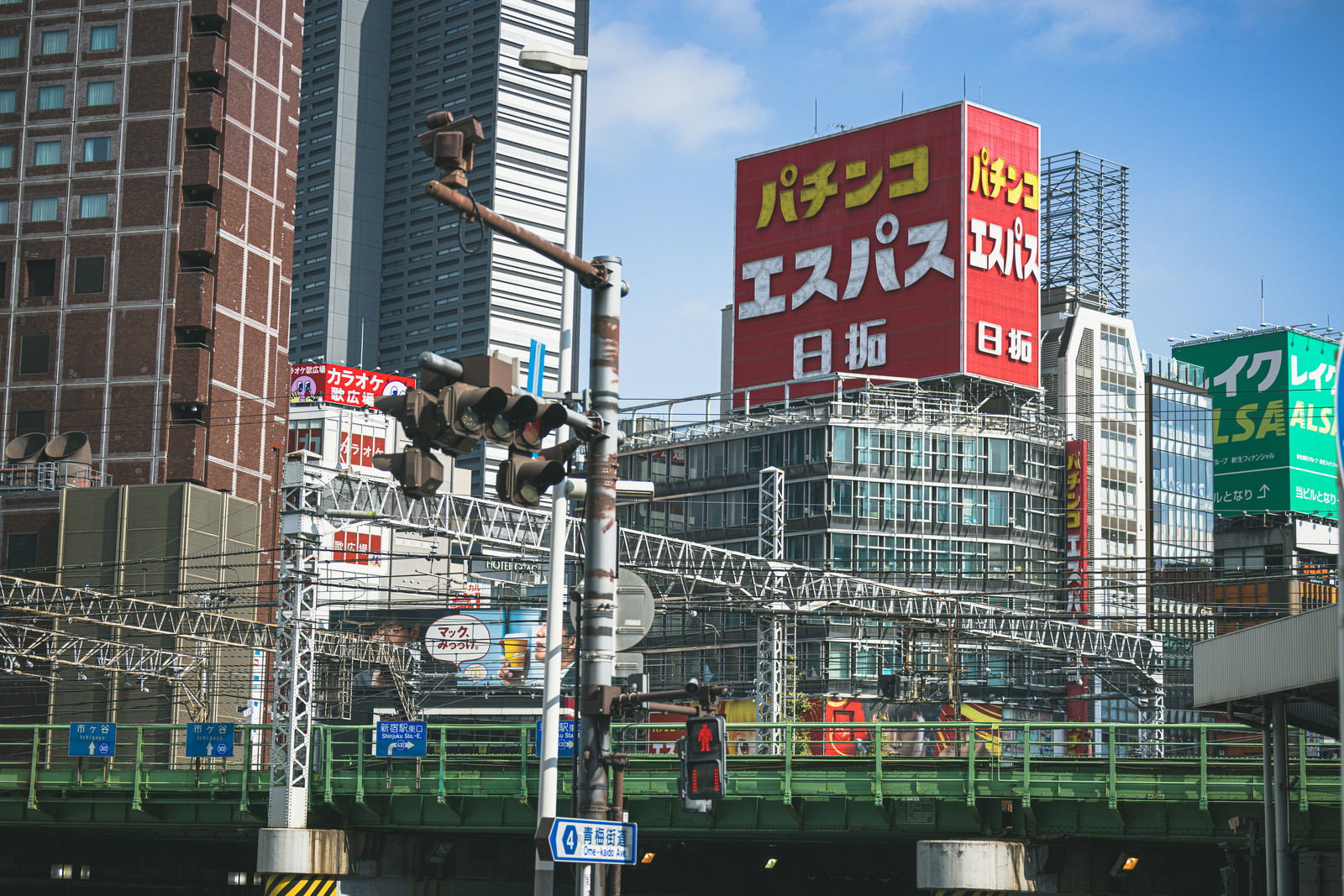 高架と電線越しに見える新宿東口の繁華街の風景