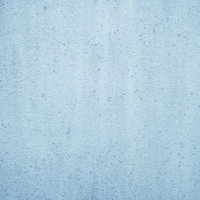 細かい斑点のシミが残る淡い青みのコンクリート壁の写真