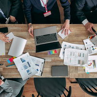 資料を広げて会議するビジネスチーム（真上から撮影）の写真