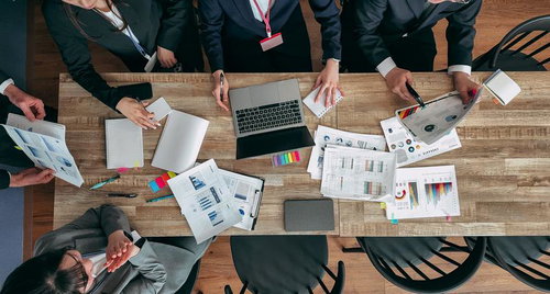 資料を広げて会議するビジネスチーム（真上から撮影）
