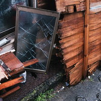 廃家から出された割れたガラスと木材の廃棄物の写真
