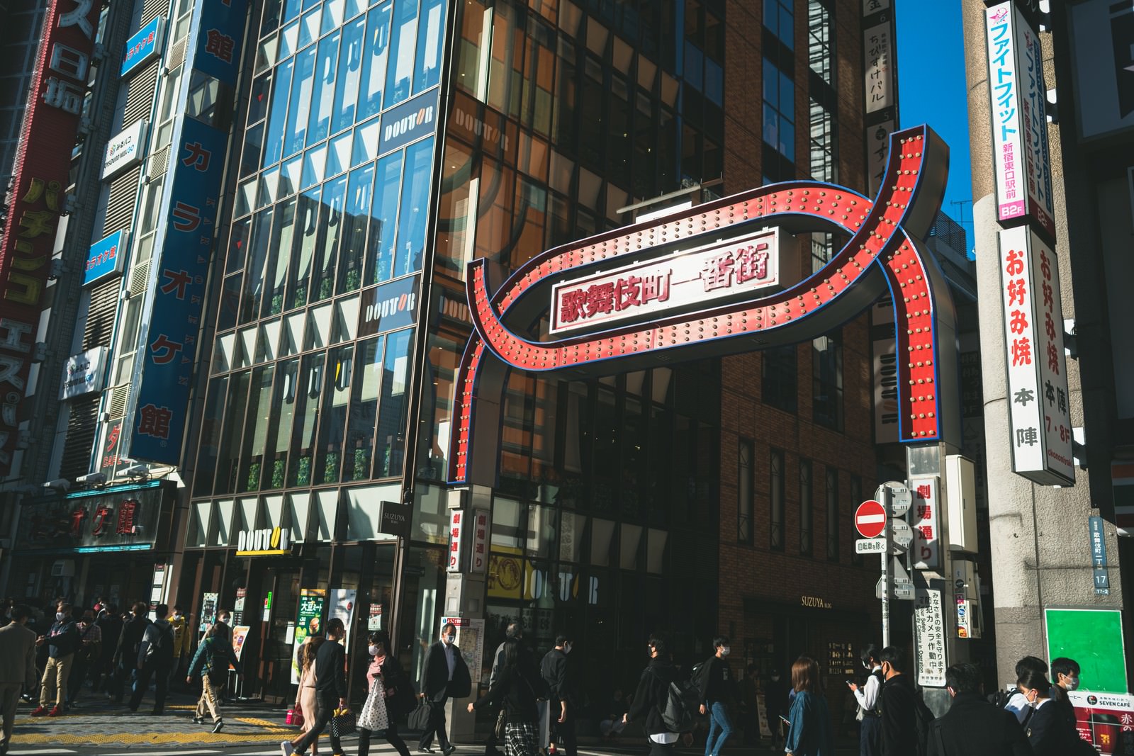 歌舞伎町一番街の赤い看板の下を歩く多くの通行人たち