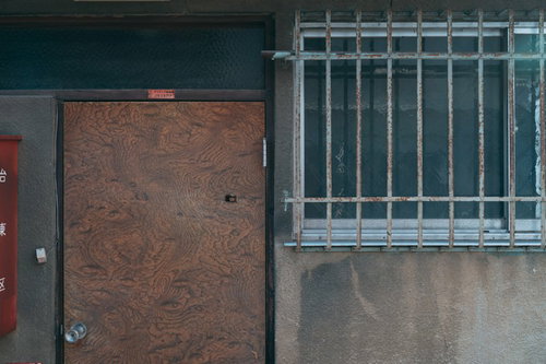 古い玄関前の茶色い扉と格子窓、木製枠の劣化した住宅