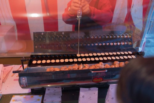 ベビーカステラを焼く出店の屋台で調理する職人