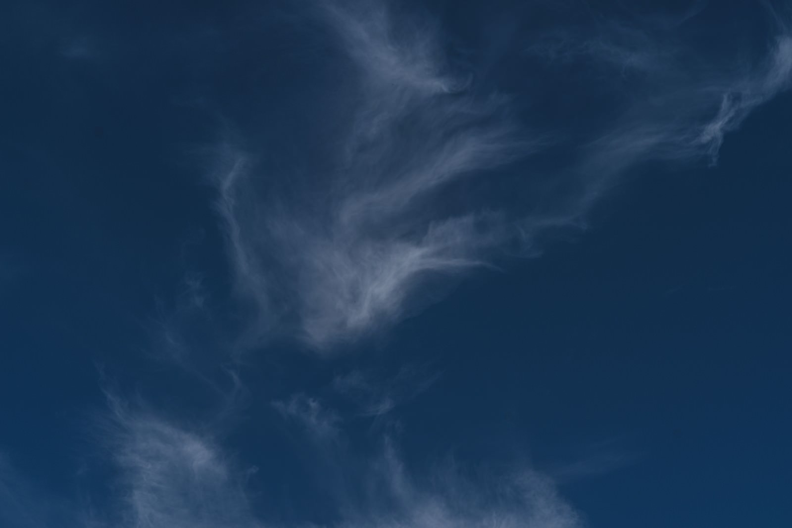 深いブルーの空に白い薄雲が流れるような形で広がる青空