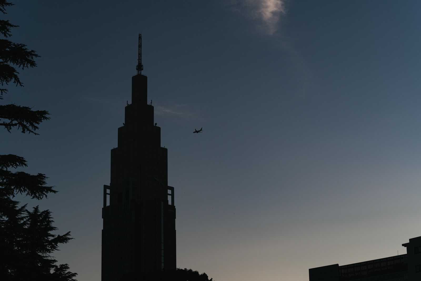 青空に映る時計台と飛行機のシルエット