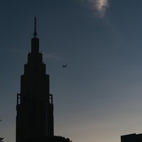 夕暮れ時の青空に映るドコモタワーと飛行機のシルエットの写真