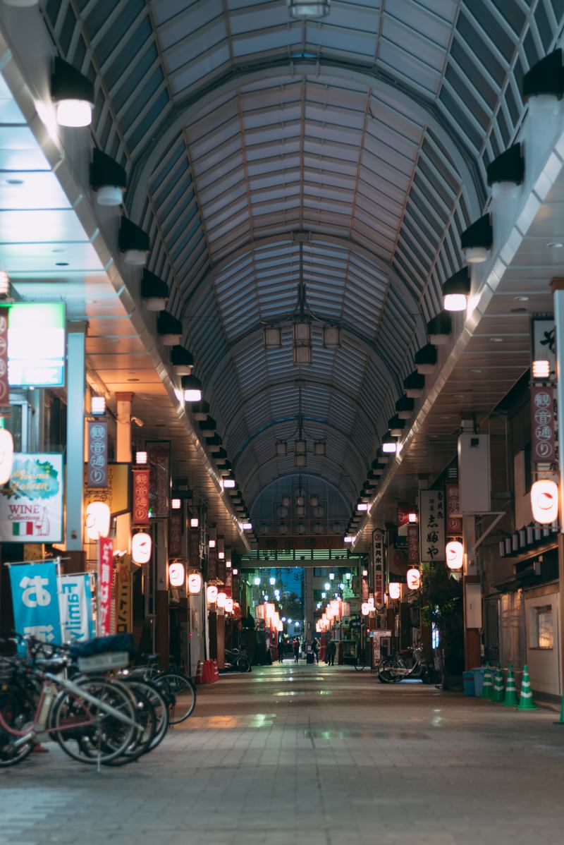 夜のアーケード街で電灯に照らされた静かな通路とシャッターが下りた店舗