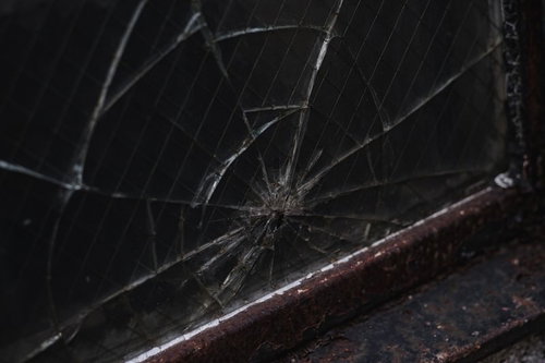 錆び付いたサッシと割れた線入りガラスの窓