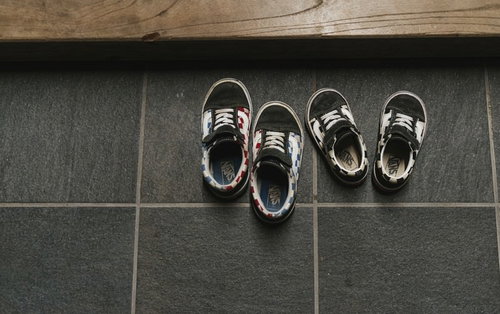 玄関のグレータイル床に脱ぎっぱなしの子供の靴のペア