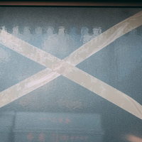 強風でガラス窓が割れないように貼られた茶色のガムテープの写真
