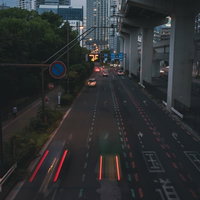 夜の国道を走る車のテールランプが描く赤い光跡の写真