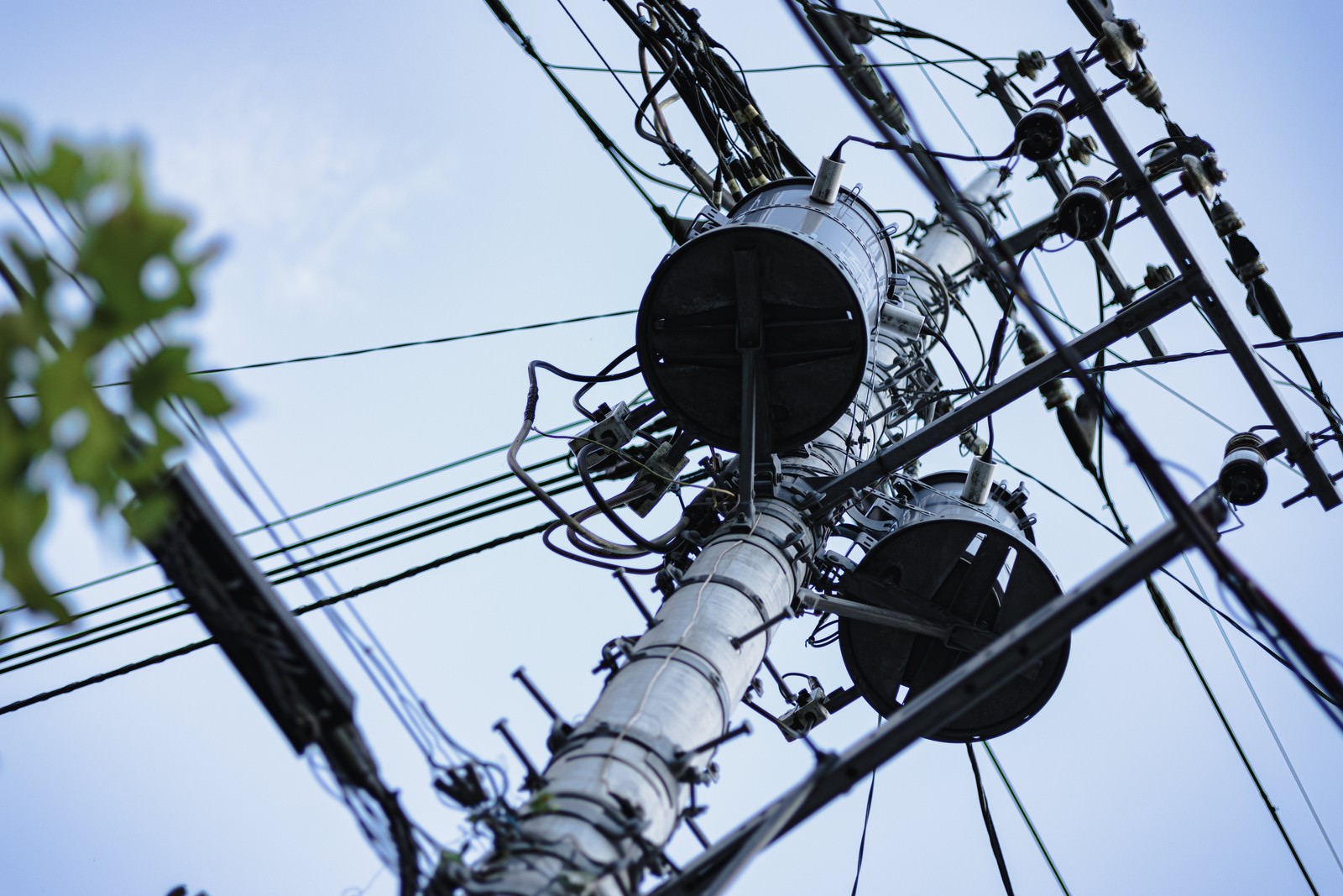 電柱の上部に設置されたグレーの柱上変圧器と電線
