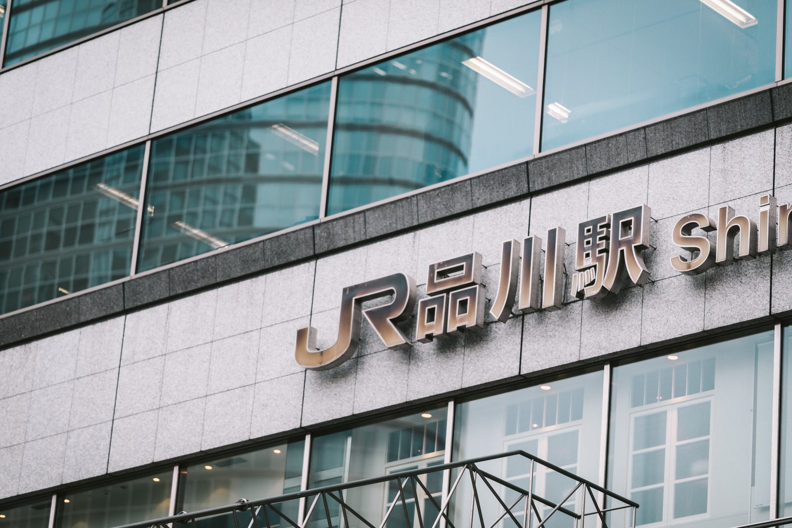 JR品川駅前のガラス張りオフィスビルと駅の看板