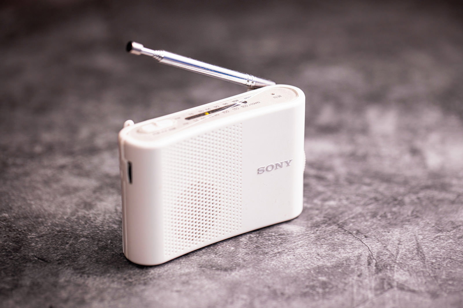 コンクリートの床に置かれた白いラジオとアンテナ