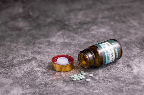 蓋の開いたルミンAの小瓶から溢れ出た黄色い錠剤