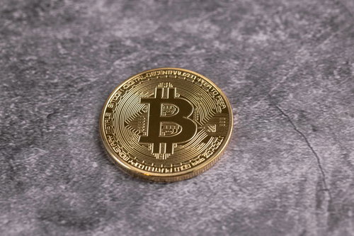 卓上に置かれた金色に輝く一枚の金貨（ビットコイン）