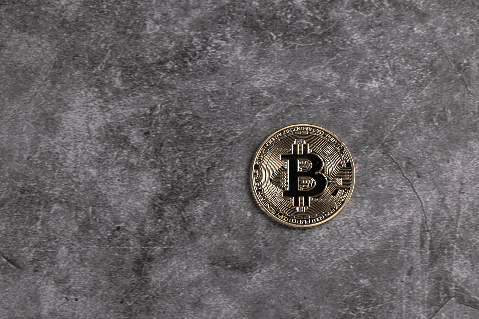 グレーのコンクリート床に置かれた金色のビットコイン