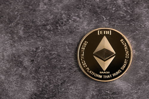 黒い石材の上で輝くETHロゴの金貨イーサリアム