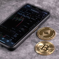 スマホのトレード画面と金貨（BTC・ETH）の写真