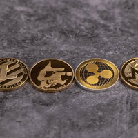 整列した四枚の暗号通貨金貨（LTC、DASH、XRP、XMR）の写真