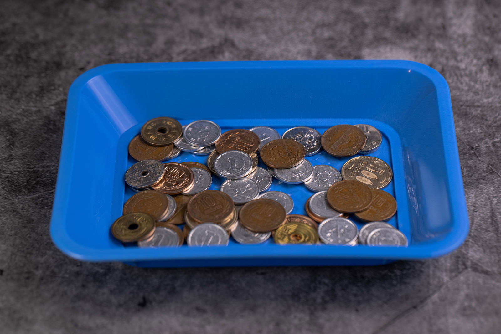 青いプラスチックトレイに大量の小銭が入っている様子