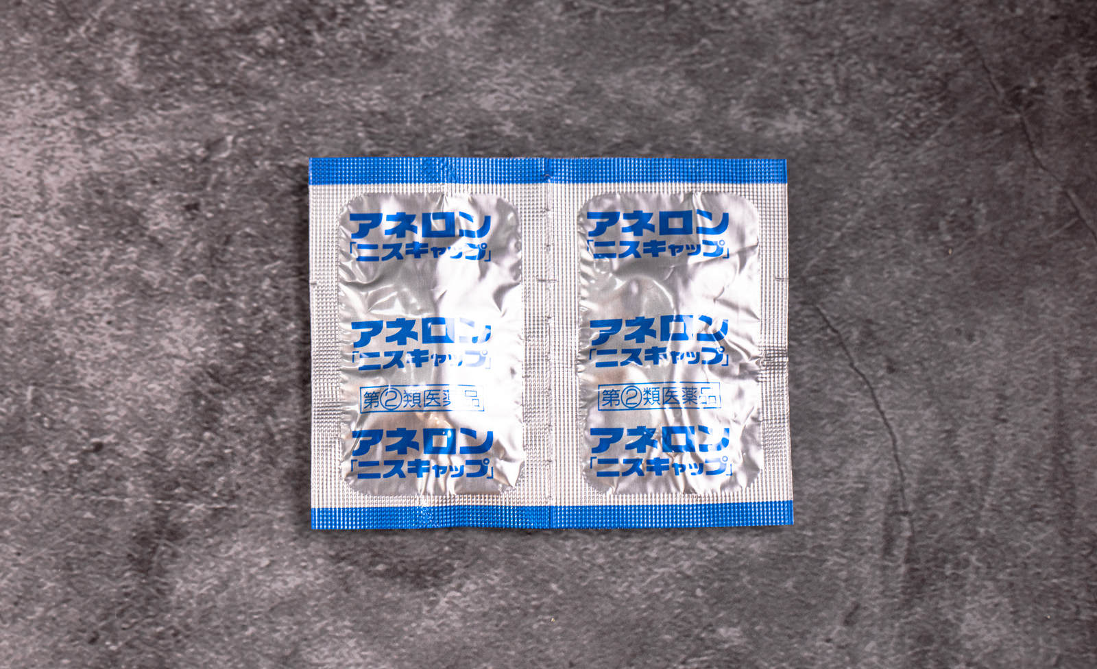 コンクリートの上に置かれた青と白のパッケージの乗り物酔い止め薬アネロン ニスキャップ2箱