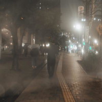 雨の夜に傘をさして歩く歩行者の写真