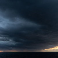 夕焼け空を覆い尽くす黒い雲と雨雲、嵐の前ぶれを示す悪天候の空の写真