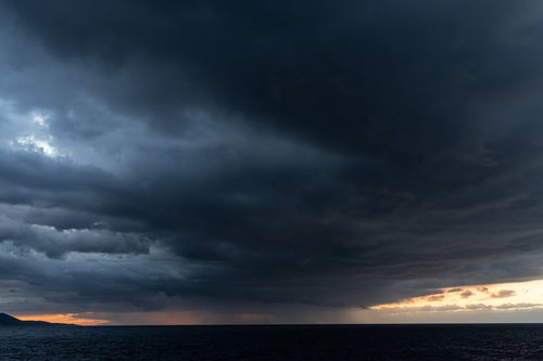 夕焼け空を覆い尽くす黒い雲と雨雲、嵐の前ぶれを示す悪天候の空