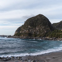 神津島・沢尻海岸の岩山と砂浜の写真