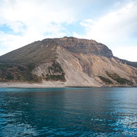 神津島の多幸湾からみる青い海と岩山の絶景の写真