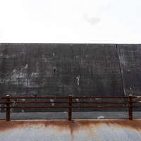 海岸の防波堤に設置された錆び付く金属製の柵の写真