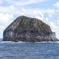 青い海に囲まれた岩山のような孤島の風景の写真