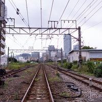街へと続く線路とレール、架線が張り巡らされた鉄道風景の写真